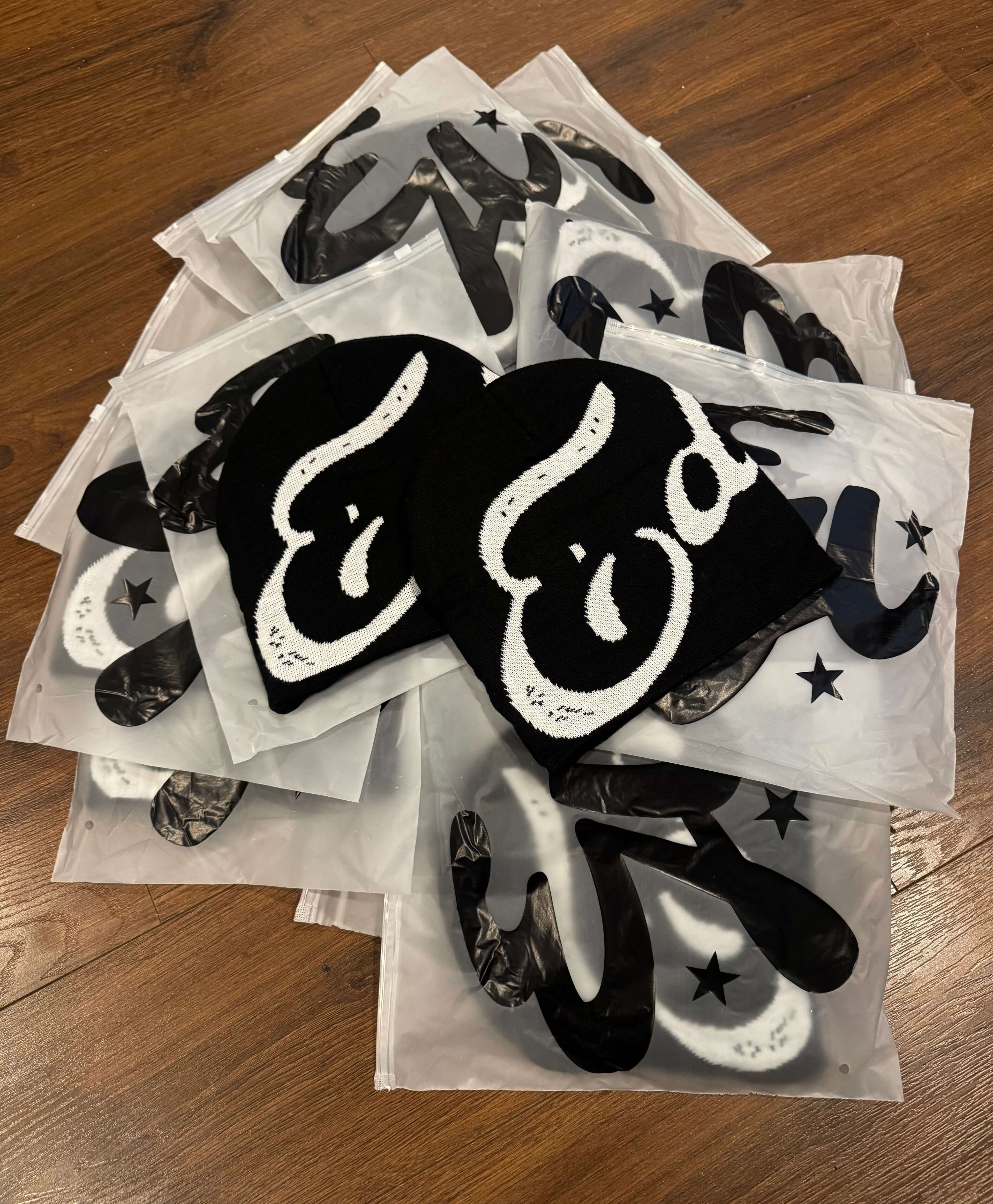 EDEN Cursive Beanie displayed on top of packaging, showcasing the design and material details.