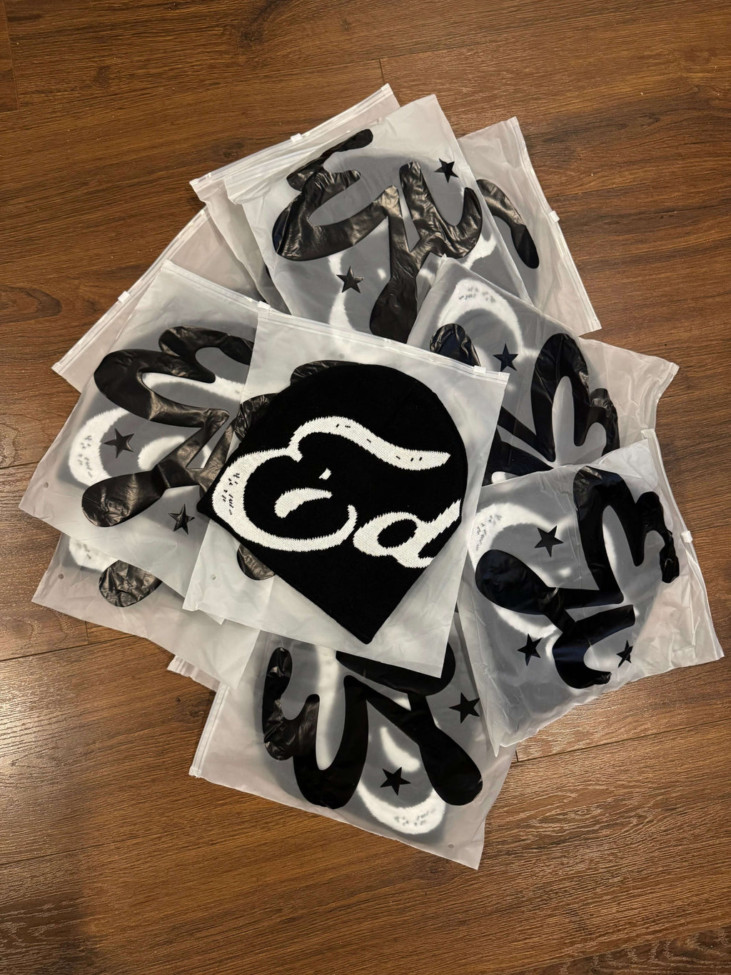 A collection of packaged EDEN Cursive Beanie designs featuring unique prints and branding.