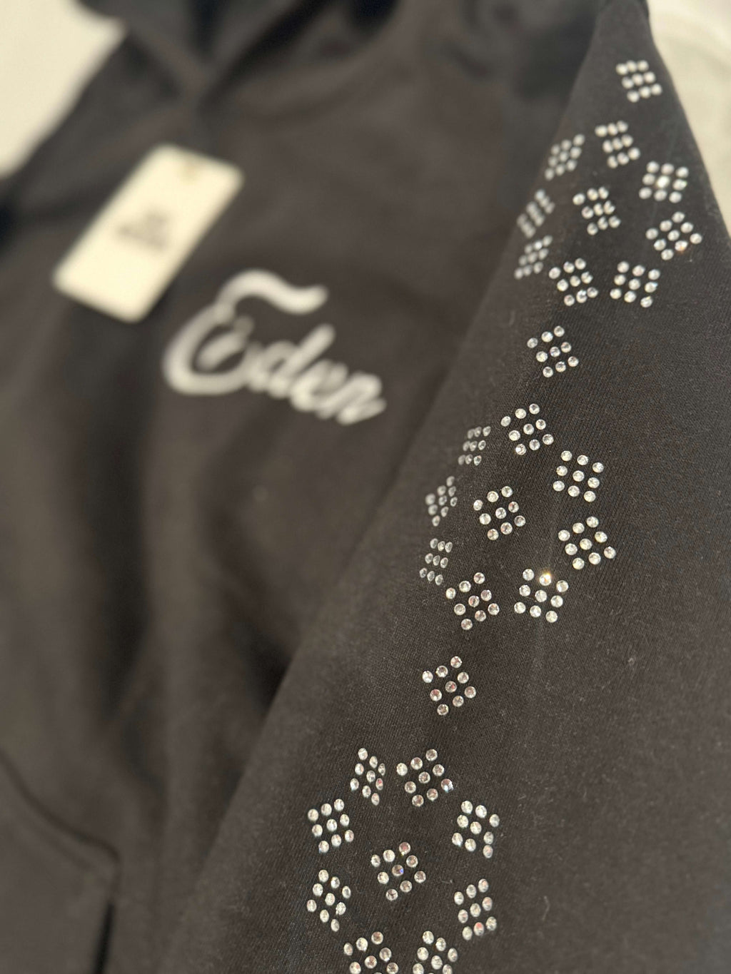 EDEN RHINESTONE SWEATSUIT featuring hand placed rhinestones on the sleeve and stylish black fabric.